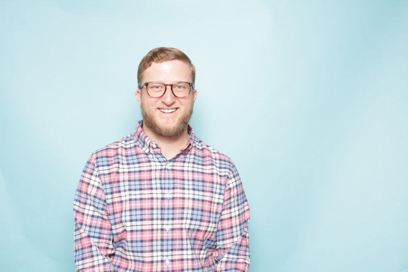 man in plaid shirt in front of blue background