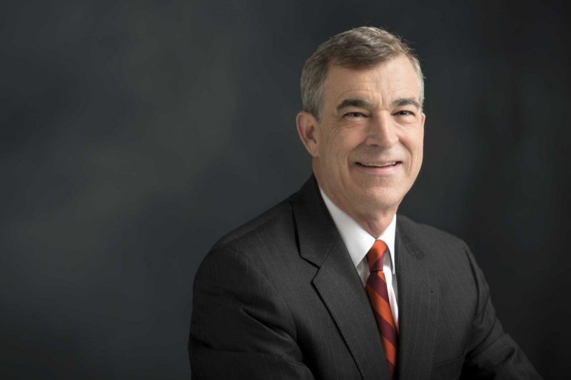 Man smiling in front of a gray background