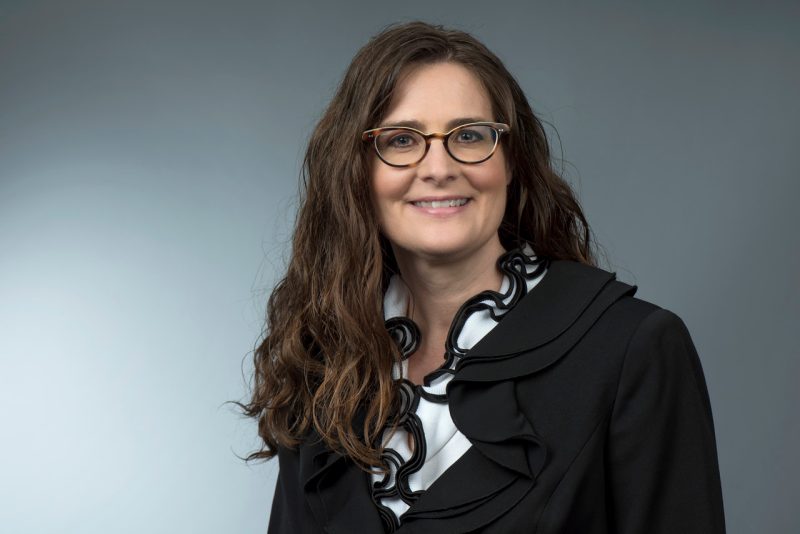 woman smiling in front of a gray background