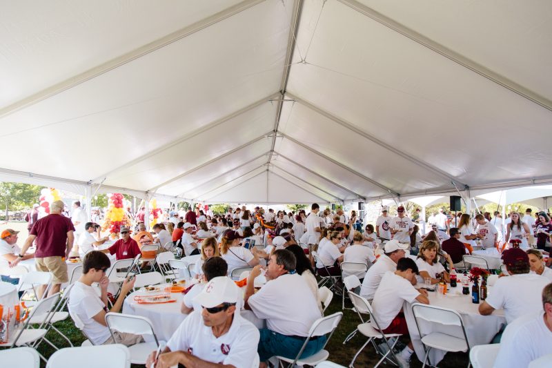 Tailgaters sit under a tent