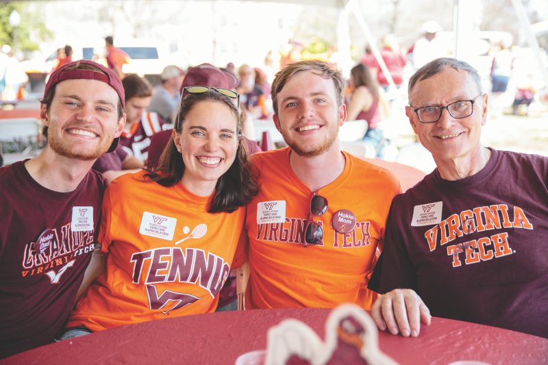 A family of Hokies smiles while sitting around a table
