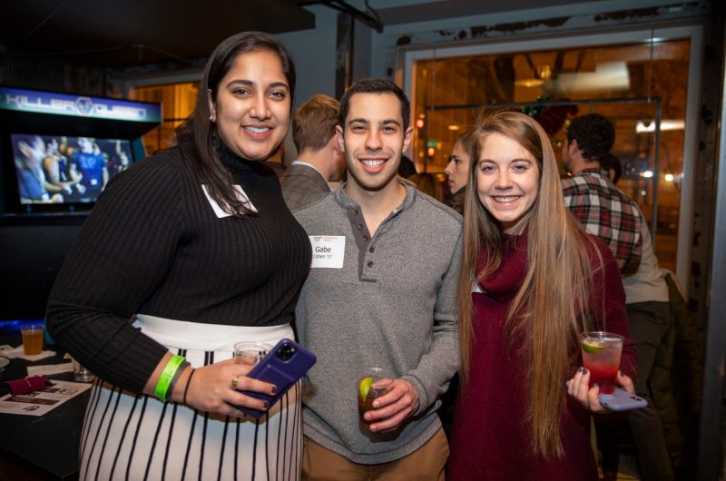 group of young alumni smiling with drinks