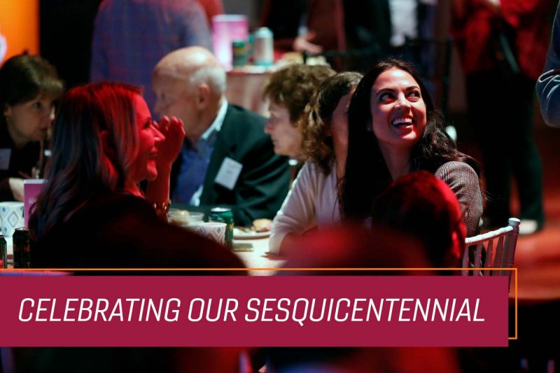 Alumni sit and talk around a table at an evening event