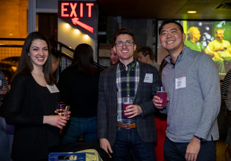 group of young alumni smiling with drinks