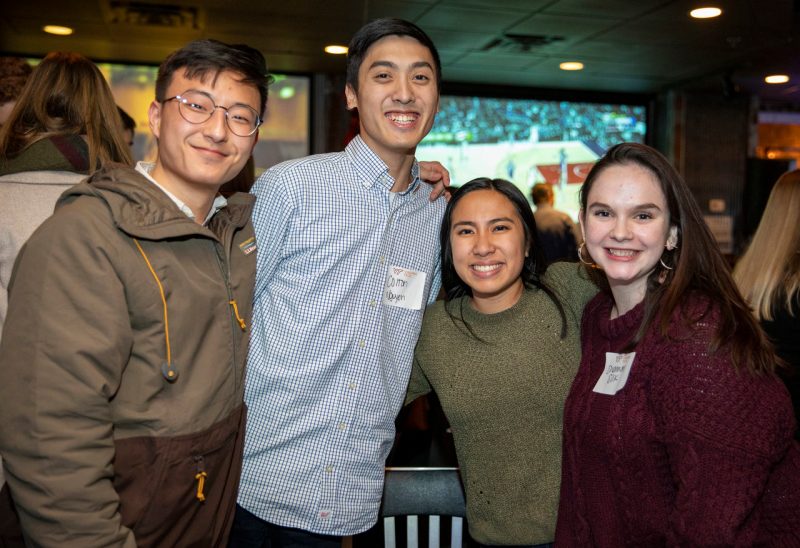four young alumni smiling