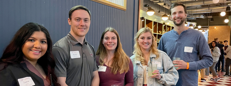 young alumni smiling with drinks