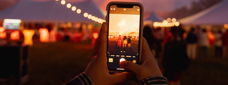 An alum takes a photo of fireworks with their phone