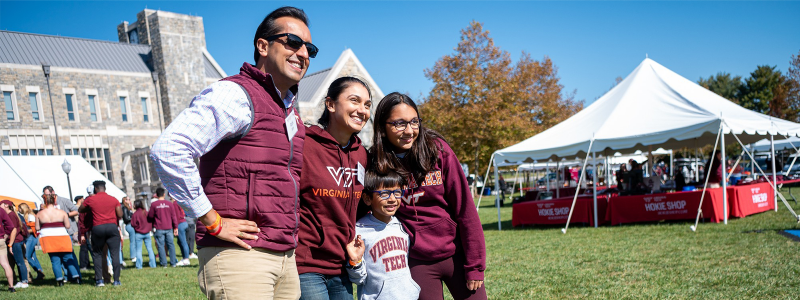A family poses for a picture on Holtzman Lawn during the Homecoming Tailgate