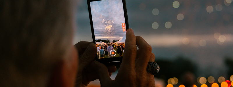 An alum takes a photo of fireworks with their phone
